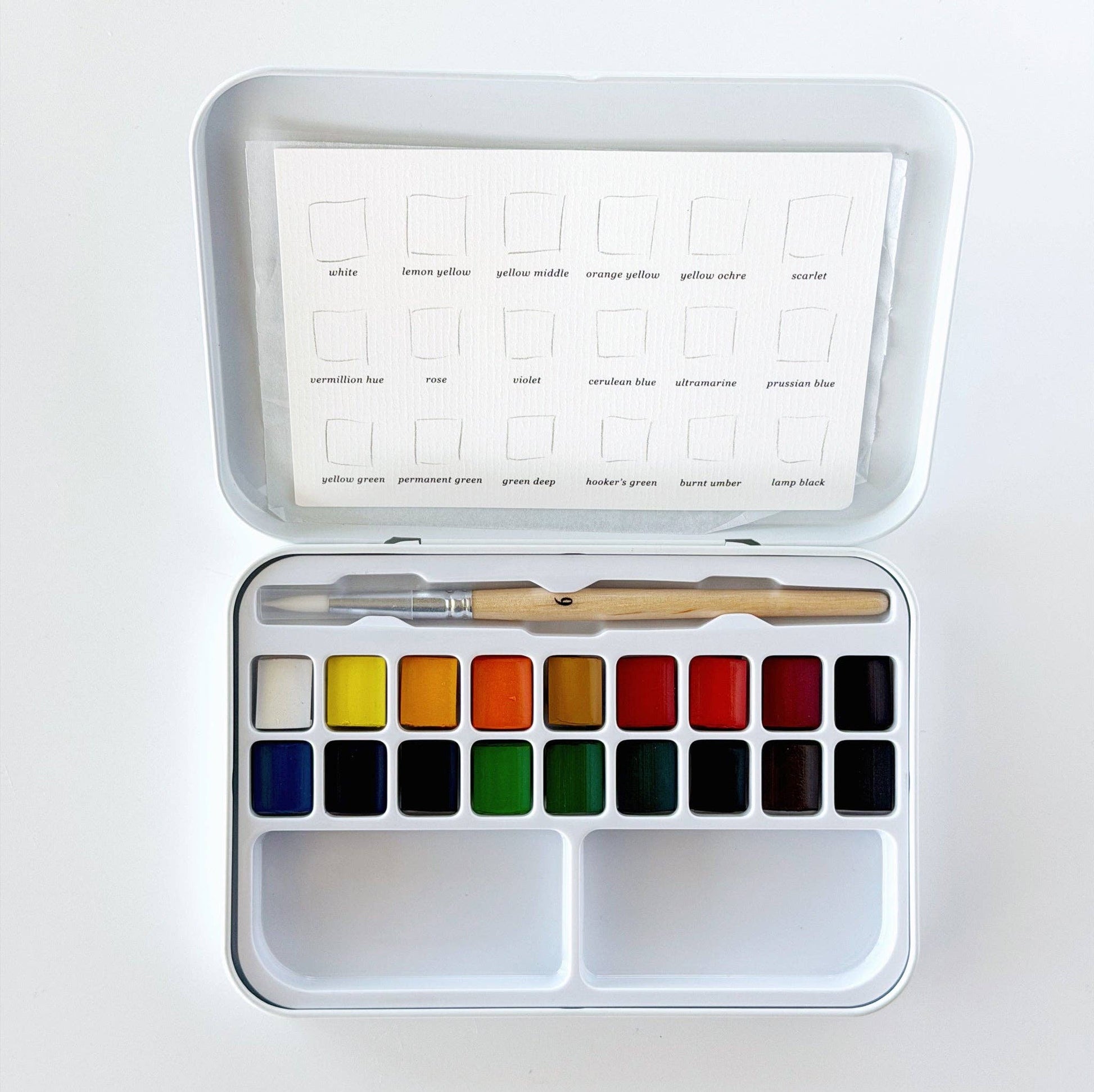 Emily Lex Watercolor Paint Set featuring 18 watercolor paints, a fold-open metal tin with mixing trays, and a petite size 6 round brush.
