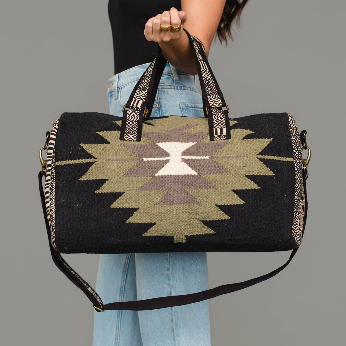 Western geometric cotton duffel bag in black, olive, gray, and cream with contrasting carrying handles.