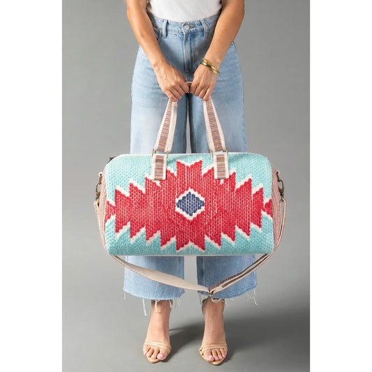 Western geometric cotton duffel bag in red, turquoise, and blue with decorative horseshoe accent.