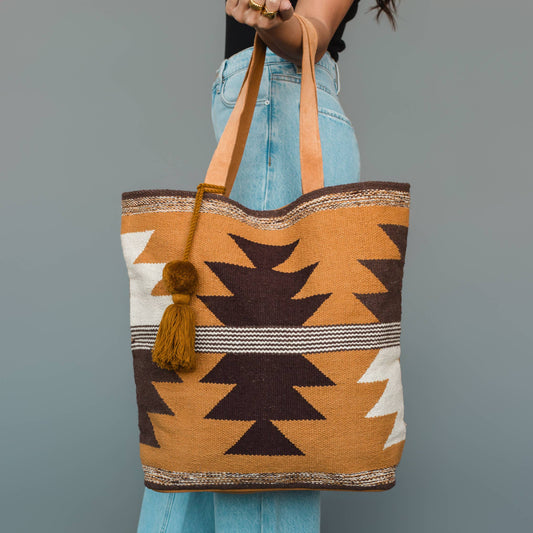 Western geometric cotton tote bag in camel, brown, and cream with tan shoulder straps and coordinating tassel.