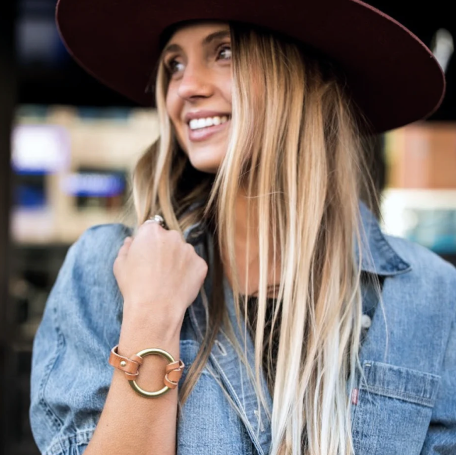 Natural leather bracelet paired with denim and layered jewelry for a timeless Western-inspired everyday look.
