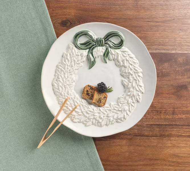 White ceramic wreath cookie plate with coordinating wooden serving tongs.
