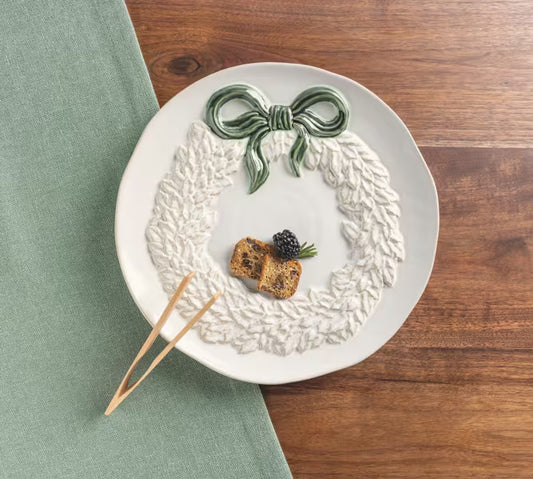 White ceramic wreath cookie plate with coordinating wooden serving tongs.