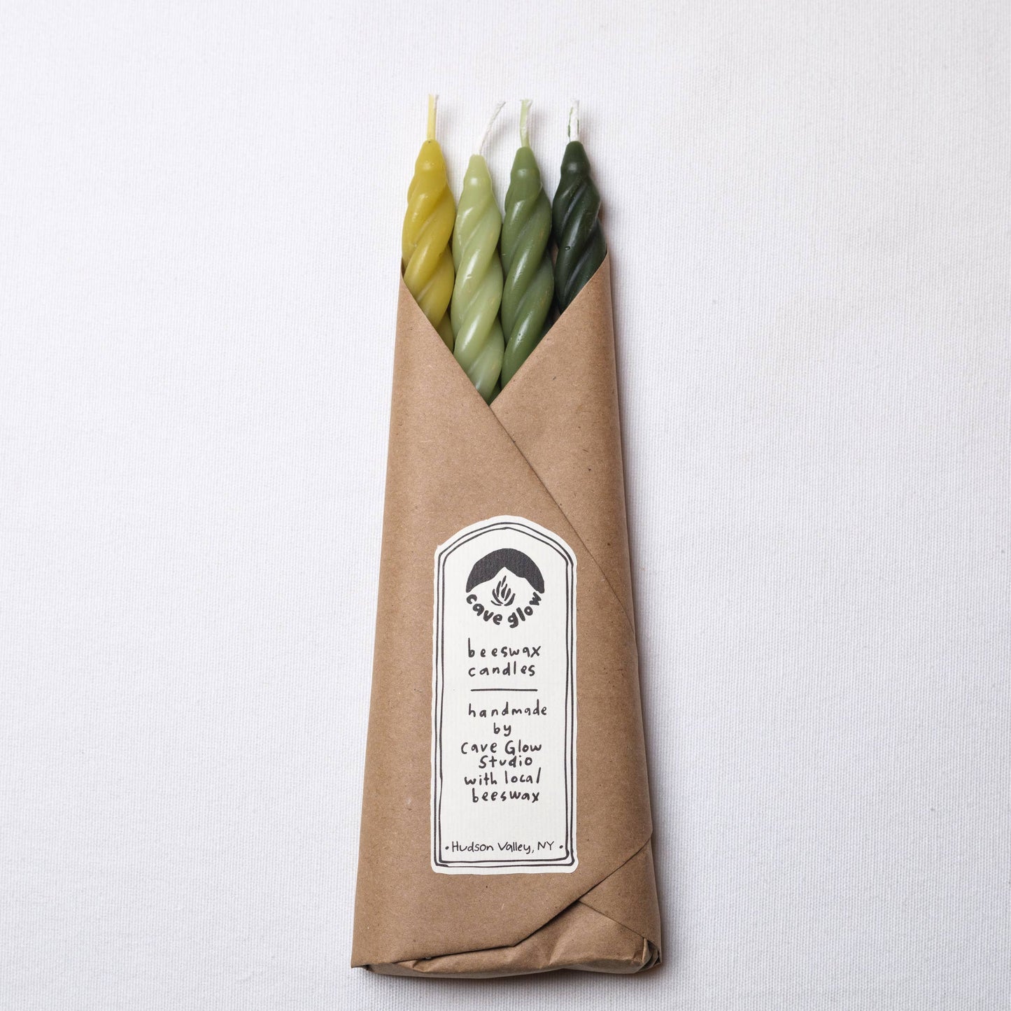Set of four handcrafted spiral beeswax taper candles in woodland-inspired shades of chartreuse, sage, grass, and pine.