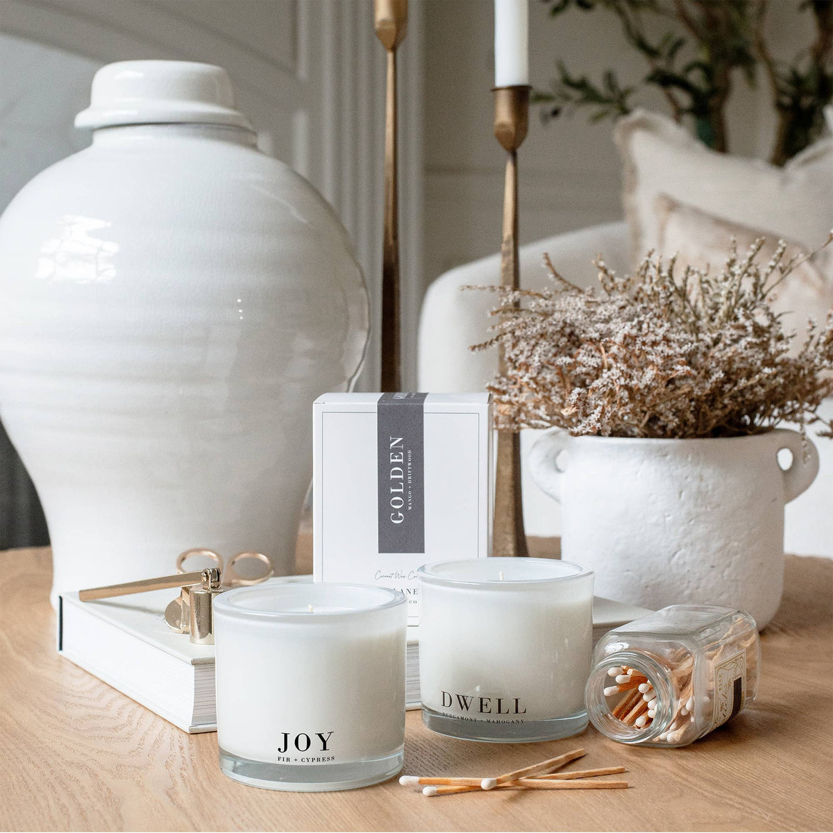 Luxury coconut wax candle styled with pine branches, brass candlesticks, vintage ornaments, and natural wood accents, creating a warm woodland-inspired Christmas atmosphere.
