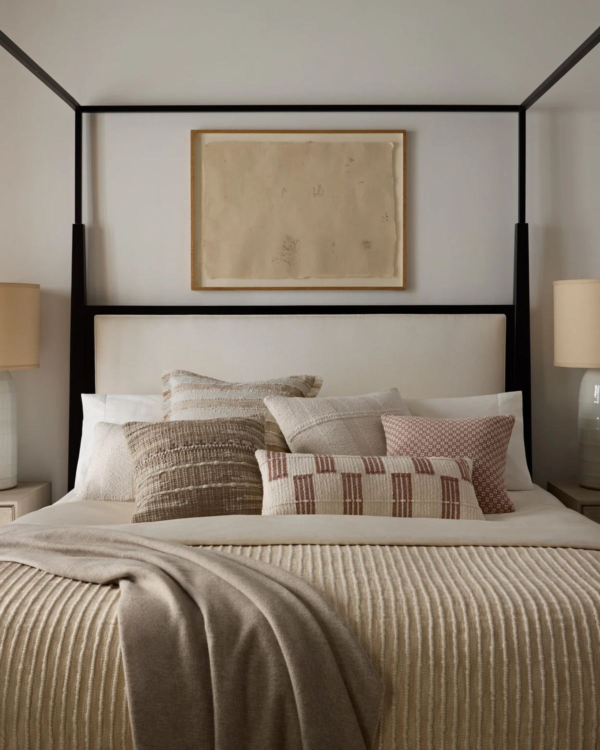 Neutral handwoven wool pillow layered on a bed with linen bedding and textured textiles, creating a warm, timeless, designer-curated retreat.