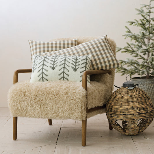 Cream and charcoal woven evergreen tree lumbar pillow styled as a cozy neutral accent on a chair.